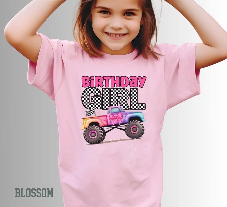 Pode incluir: Camiseta rosa claro com o texto "BIRTHDAY GIRL" em letras rosa e xadrez preto. Um gr&aacute;fico de caminh&atilde;o monstro colorido com um la&ccedil;o rosa &eacute; apresentado abaixo. A camiseta &eacute; de cor rosa claro.
