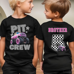 Pode incluir: T-shirts pretas com um design de monster truck. Uma camisa apresenta "PIT CREW" e um gr&aacute;fico de monster truck rosa e branco. A outra camisa diz "BROTHER 5" com um gr&aacute;fico de caminh&atilde;o correspondente. Ambas as camisas t&ecirc;m um design de bandeira quadriculada.
