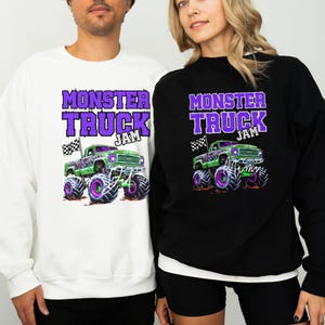 May include: Two sweatshirts with a monster truck graphic and the text "Monster Truck Jam" in purple. The sweatshirt on the left is white and the sweatshirt on the right is black.
