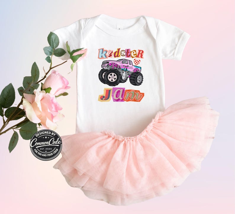 Puede incluir: Un body blanco para beb&eacute; con un gr&aacute;fico de monster truck colorido y las palabras "Kidster Jam". Combinado con una falda tut&uacute; rosa claro. El dise&ntilde;o incluye una bandera a cuadros y una fuente l&uacute;dica.
