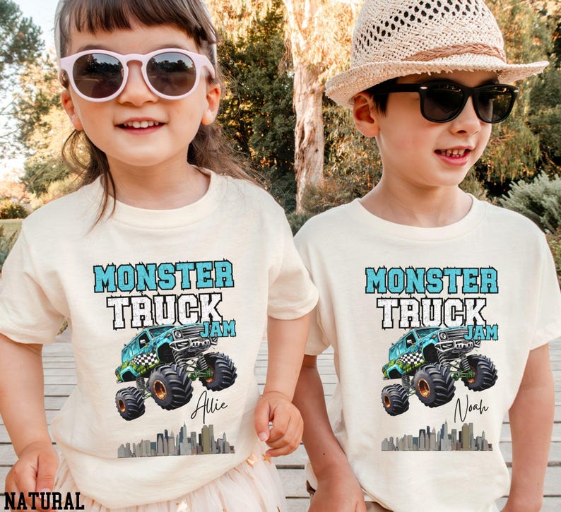 May include: Two children wearing white t-shirts with a blue monster truck graphic and the text "Monster Truck Jam". The girl's shirt says "Allie" and the boy's shirt says "Noah".
