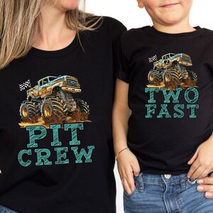 Pictured is a woman and child wearing black T-Shirts with big monster truck and checkered flags. Mom's shirt says PIT CREW in large graphic letters and boy's shirt says TWO FAST in same font