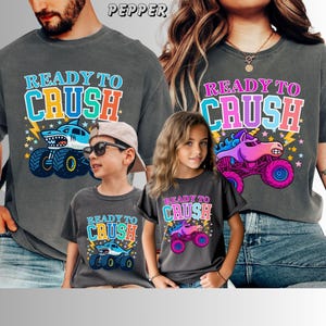 Ready to Crush Monster Truck Shirt | Comfort Colors Kids & Adult Tee | Colorful Monster Truck Shirt | Family Matching Shirts. Family of 4 has matching Monster Truck Jam themed t-shirts in Comfort Colors Brand in Pepper. The Man and Boy's say "Ready to Crush" in varsity style multi-colored letters. with a blue megalodon shark monster truck with stars and lightning. The Mom and girl's shirts say "READY to CRUSH" with a Sparkle unicorn Pink Smash Monster Truck with stars and lightning.