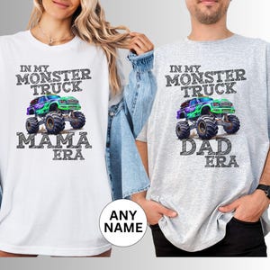 May include: White and grey t-shirts with a monster truck graphic. The white shirt says "In My Monster Truck Mama Era" and the grey shirt says "In My Monster Truck Dad Era". The graphic features a colourful monster truck.