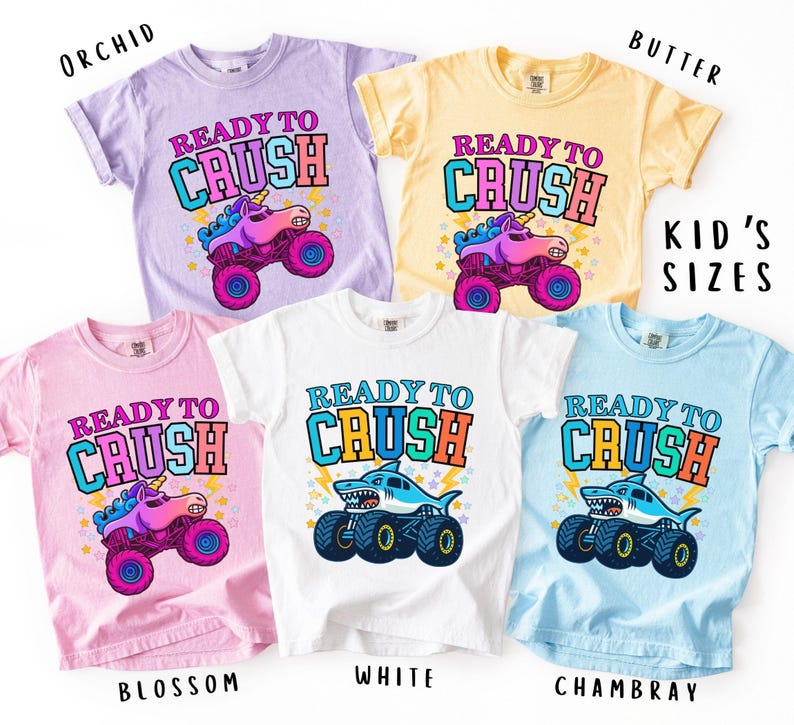 May include: Five colorful t-shirts with the text "READY TO CRUSH" and graphic designs. The shirts are in orchid, butter, blossom, white, and chambray. The designs include a unicorn monster truck and a shark monster truck.