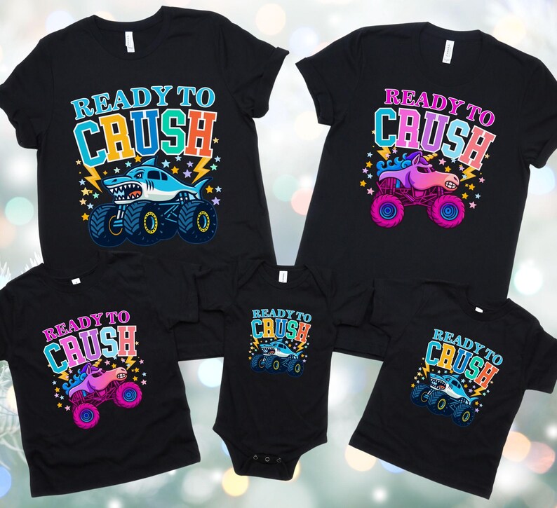 Pode incluir: T-shirts pretas e um body com o texto "READY TO CRUSH" e gr&aacute;ficos de monster truck. Os monster trucks s&atilde;o em v&aacute;rias cores, incluindo azul, rosa e roxo. As camisas s&atilde;o para tamanhos diferentes.