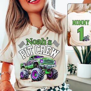May include: A beige t-shirt with the text "Noah's PIT CREW" and a green monster truck graphic. The truck has purple and green accents. The back of the shirt has the word "MOMMY", the number "1", and a monster truck graphic.