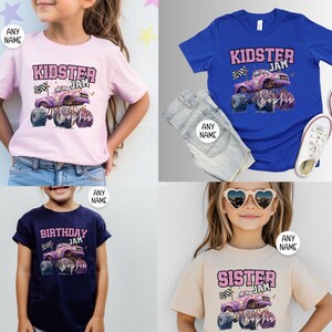 May include: A selection of children's t-shirts in different colours, each displaying a monster truck graphic with the text "Kidster Jam", "Birthday Jam", or "Sister Jam". The shirts are in pink, blue, navy, and beige.