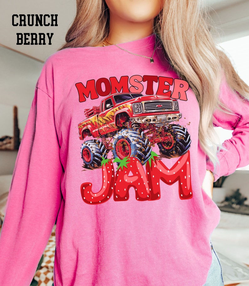 May include: Pink long-sleeved shirt with a graphic of a red monster truck with flames and the text "Momster Jam" in red letters with strawberry accents.