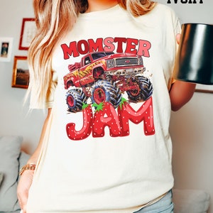 May include: A white t-shirt with a red monster truck graphic and the text "Momster Jam" in red and white letters. The truck is driving through a strawberry field.