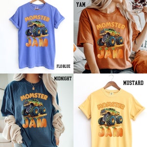 May include: Four different colored t-shirts with a graphic of a monster truck and the text "MOMSTER JAM" printed on the front. The t-shirts are in the colors: flo blue, mustard, yam, and midnight.