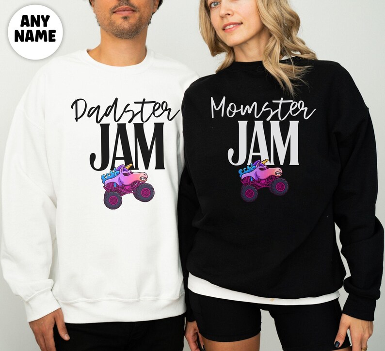 May include: White and black sweatshirts with the text "Dadster JAM" and "Momster JAM" in a script font. Each sweatshirt features a colorful monster truck graphic. The sweatshirts are worn by two people.