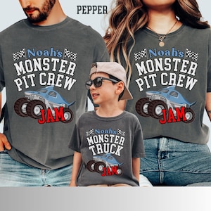 Puede incluir: Camisetas grises con tem&aacute;tica de monster truck. Las camisetas muestran el texto "Noah's MONSTER PIT CREW JAM" y "Noah's MONSTER TRUCK JAM" con un gr&aacute;fico de monster truck con tem&aacute;tica de tibur&oacute;n. Las camisetas son usadas por una familia.