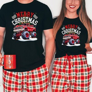 May include: Black t-shirts with a Christmas monster truck graphic. The shirts feature the text "Merry Christmas" and are paired with red plaid pajama pants. One person holds a red mug that says "Merry & Bright".