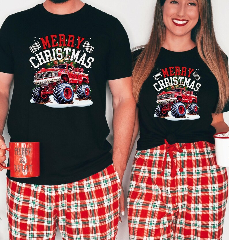 May include: Black t-shirts with a Christmas monster truck graphic. The shirts feature the text "Merry Christmas" and are paired with red plaid pajama pants. One person holds a red mug that says "Merry & Bright".