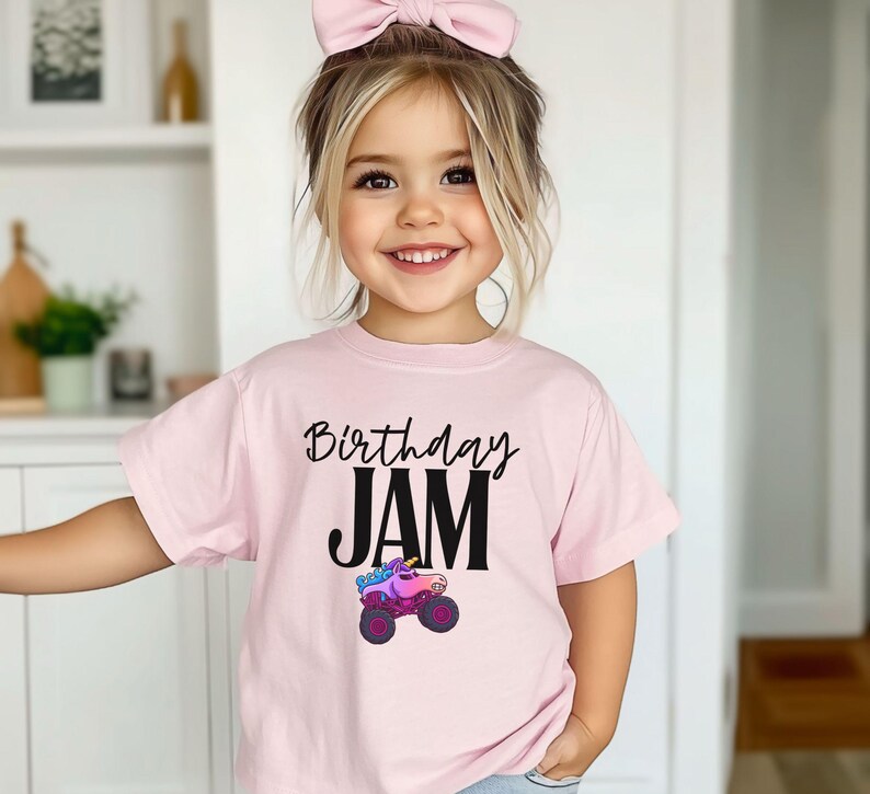 Personalized Name Girls Monster Truck Jam Sparkle Unicorn Smash Tee. Little girl is wearing a pink t-shirt that says "Birthday Jam" with a Unicorn Monster Truck with Rainbow Colors in Pink, Purple and Blue Colors. Cartoon style Big Truck with Birthday in Cursive Handwriting and Jam in Big Bold Letters in Black.
