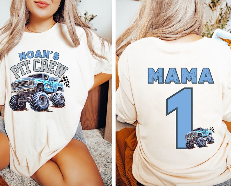 Cream-colored t-shirt featuring a blue monster truck graphic with the text "NOAH'S PIT CREW" on the front. The back of the shirt displays the word "MAMA" above a large number "1" and a smaller monster truck graphic.