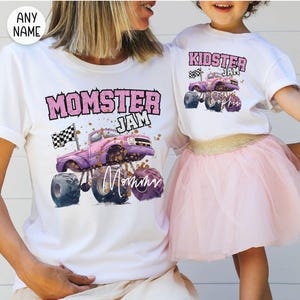 May include: White t-shirts with matching designs. One shirt says "Momster Jam" with a purple monster truck graphic and the word "Mommy". The other shirt says "Kidster Jam" with a similar truck graphic and the name "Sophia".