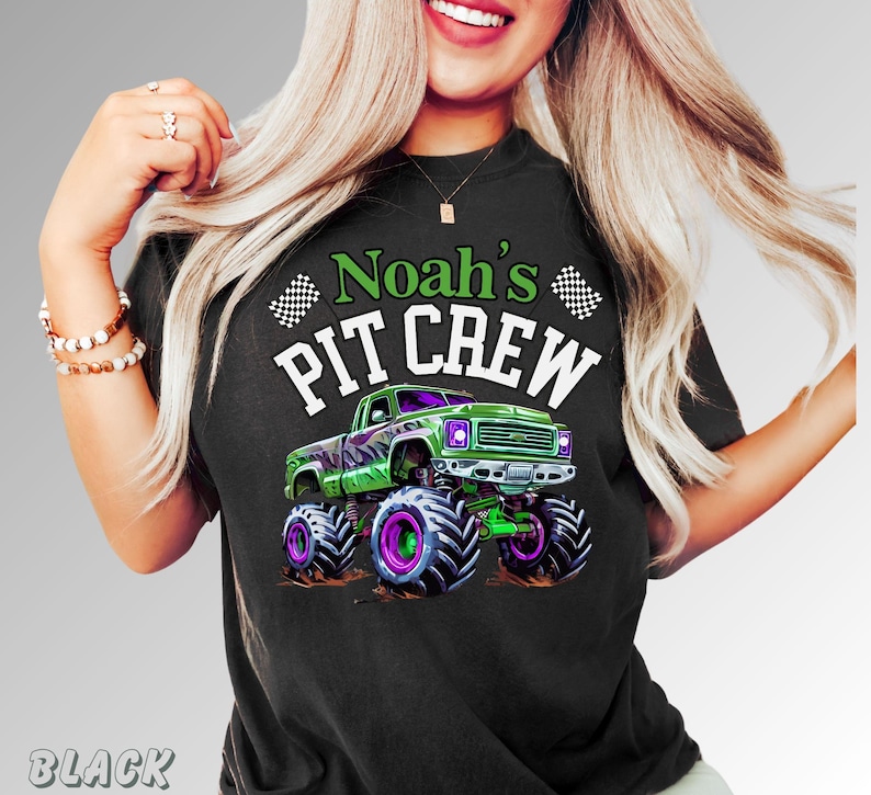 Pode incluir: Camiseta preta com um gr&aacute;fico de um monster truck verde e roxo. O texto "Noah's PIT CREW" est&aacute; acima do caminh&atilde;o. Bandeiras quadriculadas em ambos os lados do texto.