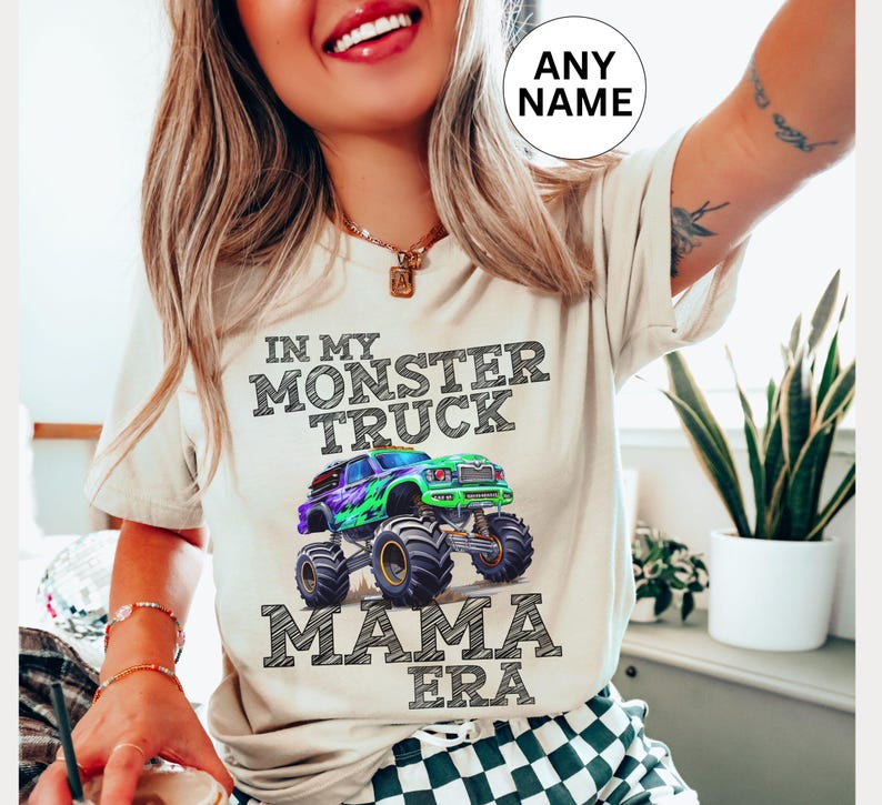 model is wearing a natural colored t-shirt with black chalk art letters saying " In My Monster Truck Mama Era" with a green and purple truck. Personalized Name shirt. Family Matching. Monster Truck Jam Pit Party Theme. Digger.