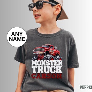 May include: A dark gray t-shirt with a red monster truck graphic and the text "Monster Truck Carson" in white.
