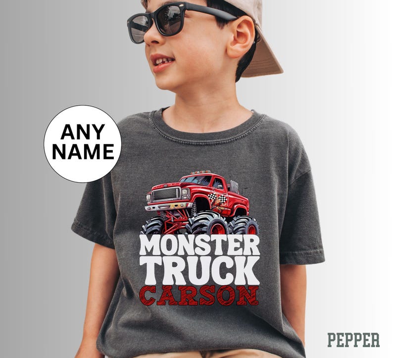 May include: A dark gray t-shirt with a red monster truck graphic and the text "Monster Truck Carson" in white.