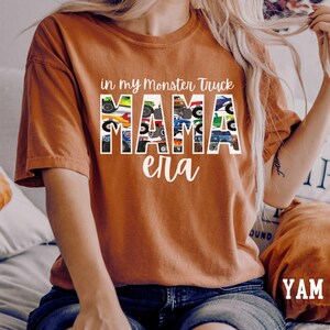 Puede incluir: Una camiseta marr&oacute;n con el texto "in my monster truck mama era" impreso en ella. El texto est&aacute; formado por im&aacute;genes de monster trucks.