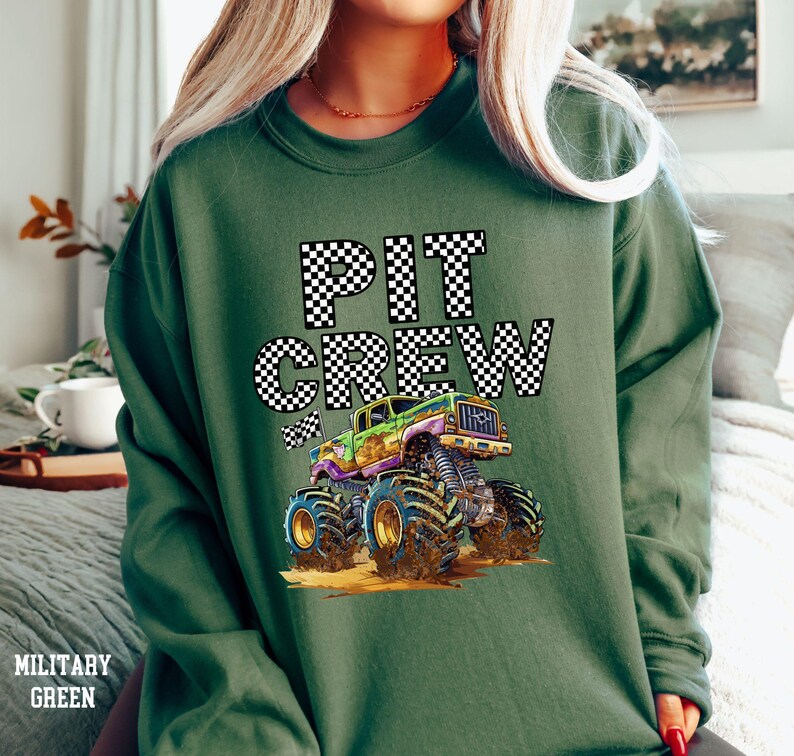 May include: Green sweatshirt with a black and white checkered "PIT CREW" graphic and a cartoon monster truck.