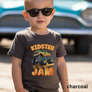 May include: A charcoal gray t-shirt with a cartoon monster truck graphic and the text "Kidster Jam".