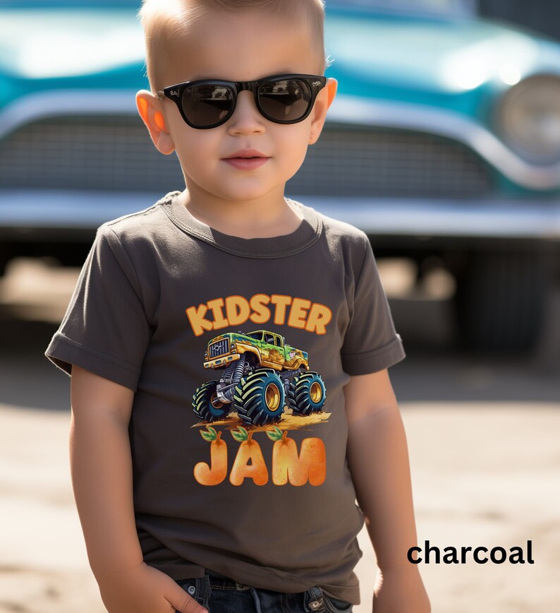 May include: A charcoal gray t-shirt with a cartoon monster truck graphic and the text "Kidster Jam".