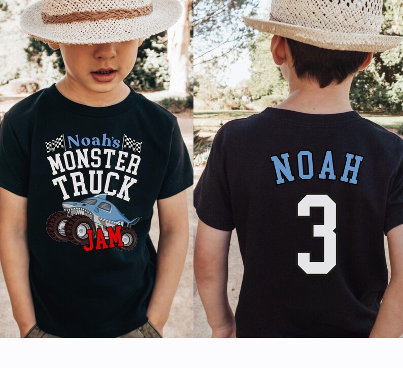 以下が含まれることがあります： サメと「Noah's Monster Truck Jam」の文字が入った、モンスター トラックのグラフィックが特徴の黒いTシャツ。Tシャツの背面には、名前「Noah」と数字「3」が青と白で表示されています。