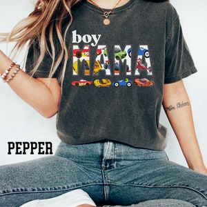 May include: A dark gray t-shirt with the text "boy mama" in white letters. The letters are made up of small toy cars in various colors.