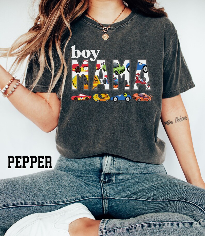 May include: A dark gray t-shirt with the text "boy mama" in white letters. The letters are made up of small toy cars in various colors.