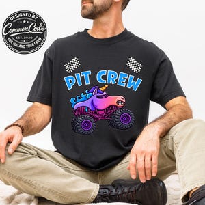 May include: Black t-shirt with the words "PIT CREW" in blue and white, featuring a cartoon unicorn monster truck. The unicorn is purple, pink, and blue, with a yellow horn. Checkered flags are on the top of the shirt.