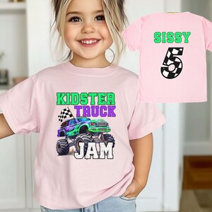 Puede incluir: Camiseta rosa con un gr&aacute;fico de cami&oacute;n monstruo verde, morado y negro y el texto "Kidster Truck Jam". Una segunda camiseta rosa con el texto "Sissy 5" en verde y negro.