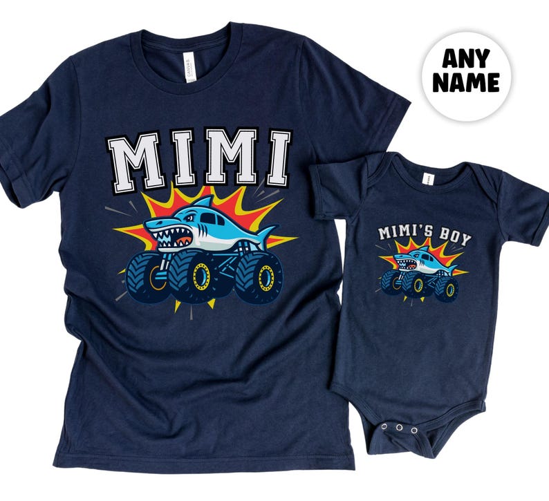 Pictured is a t-shirt adult size in Navy that says "MIMI" and a baby bodysuit in navy that says "Mimi's Boy" - both have a shark monster truck underneath with an explosion of orange and yellow behind the truck. Any Custom Name. Family Sizes available.
