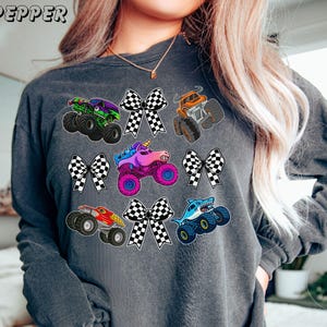 soft vintage long sleeve comfort color tee in pepper with monster truck collage of checkered bows and monster trucks.