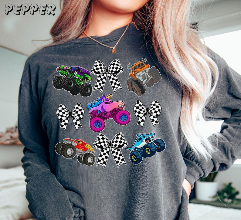 soft vintage long sleeve comfort color tee in pepper with monster truck collage of checkered bows and monster trucks.