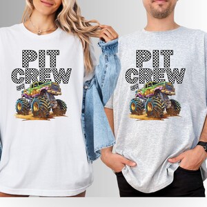 May include: White and gray t-shirts with the text "PIT CREW" above a colorful monster truck graphic. The monster truck has large tires and is in a dirt setting. The shirts are casual wear.