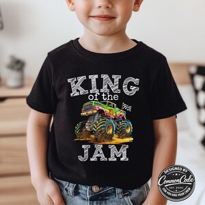 May include: Black t-shirt featuring a colourful monster truck graphic and the text "KING of the JAM". The monster truck is green, pink, and blue. The shirt also has the text "DESIGNED BY Common Code EST. 2020 FOR YOU AND YOUR CREW".