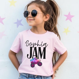 Girl is wearing a pink Monster Truck Jam t-shirt that has a unicorn Monster Truck Jam Themed t-shirt that says "Sophia" Jam with a unicorn Monster Truck in Rainbow Colors of Pink, Purple and Blue in a cartoon style drawing. The name is fully customizable in a cursive style font, JAM is in a bold block print. The letters are in black. Comes Family Matching sizes perfect for birthday Girl Parties, Race Day, Truck Show apparel.