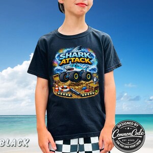 Puede incluir: Camiseta negra con un gr&aacute;fico colorido de "SHARK ATTACK" que muestra un cami&oacute;n monstruo tibur&oacute;n. El dise&ntilde;o incluye cofres del tesoro, un salvavidas y el texto "DESIGNED BY COMMON CODE FOR YOU AND YOUR CREW EST. 2020".