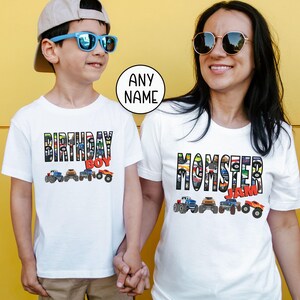 Op de afbeelding: Witte T-shirts met een monstertruckthema. Het shirt voor kinderen zegt "Birthday Boy" met een rij monstertrucks. Het shirt voor volwassenen zegt "Momster Jam" met een rij monstertrucks.