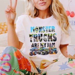 May include: White t-shirt with a graphic of monster trucks and the text "Monster Trucks Are My Jam".