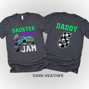 Puede incluir: Dos camisetas de color gris oscuro jaspeado. Una camiseta tiene un gr&aacute;fico de cami&oacute;n monstruo con el texto "DADSTER TRUCK JAM". La otra camiseta tiene el texto "DADDY" y el n&uacute;mero "5" en un patr&oacute;n a cuadros.