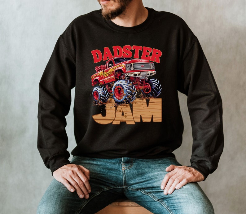 May include: Black sweatshirt featuring a graphic of a red monster truck with blue and red wheels, and the text "DADSTER JAM" in red and brown. The design has a vintage, cartoonish style.