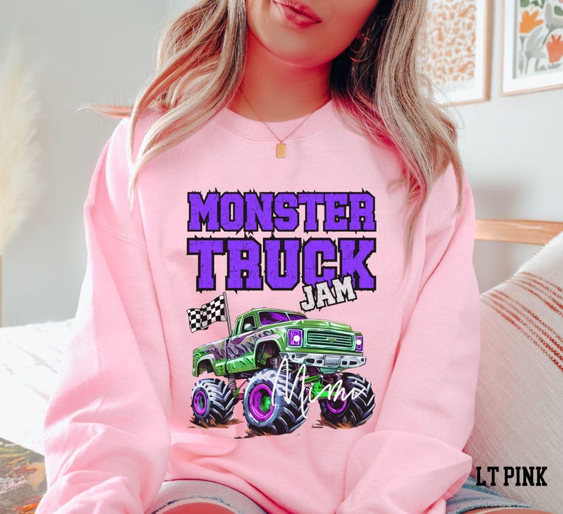 May include: Pink sweatshirt with a purple and green monster truck graphic and the text "Monster Truck Jam".