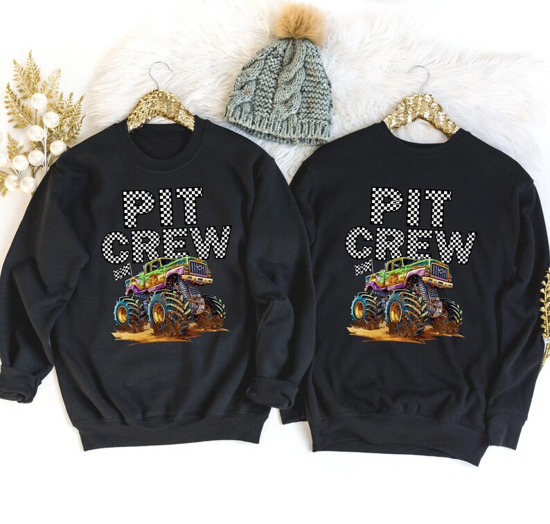 May include: Two black sweatshirts with a monster truck graphic and the text "PIT CREW" in white with black checkered flag accents.