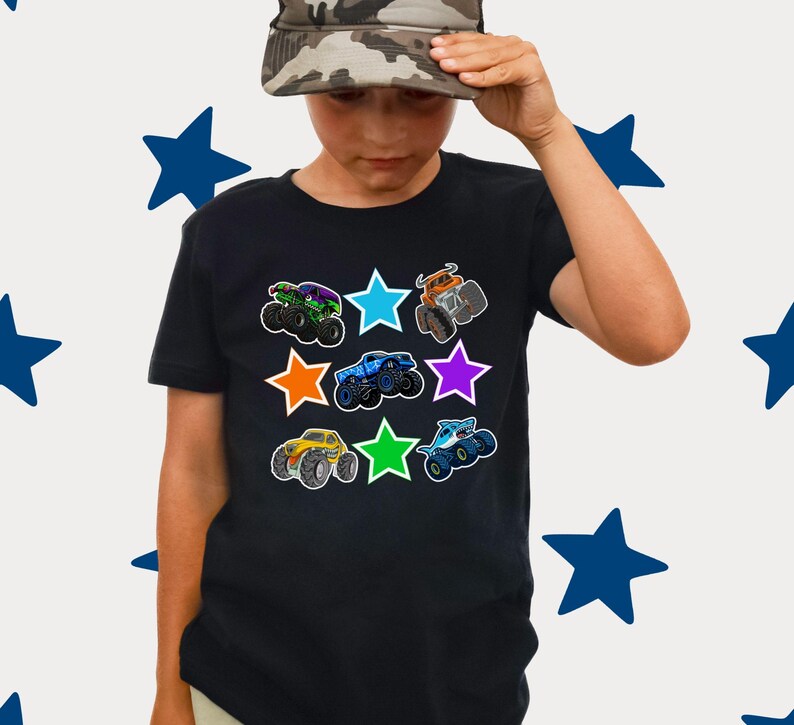 Może przedstawiać: Czarny t-shirt z kolorowymi grafikami monster truck&oacute;w otoczonymi gwiazdami. Ciężar&oacute;wki są w r&oacute;żnych kolorach, w tym zielonym, niebieskim, pomarańczowym i ż&oacute;łtym. Koszulka ma okrągły dekolt.