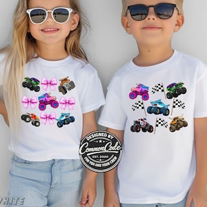 以下が含まれることがあります： カラフルなモンスタートラックのデザインが施された白いTシャツ。ユニコーン、サメ、レーシングカーなど、さまざまなテーマのモンスタートラックが描かれています。シャツには「DESIGNED BY COMMON CODE EST. 2020 FOR YOU AND YOUR CREW」の文字も入っています。